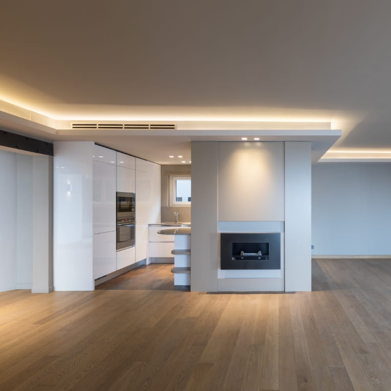 Modern interior featuring a suspended ceiling with recessed lighting and a sleek partition wall with a built-in fireplace â€” illustrating stylish space division and functional ceiling design in a contemporary kitchen-living area.