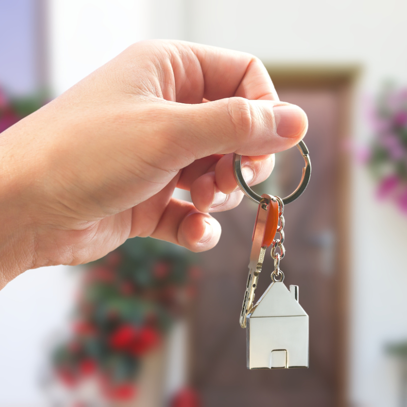 Symbolic representation of turnkey interior finishing â€” close-up of a hand holding a house-shaped keychain and key, evoking the handover of a fully furnished and move-in-ready property.